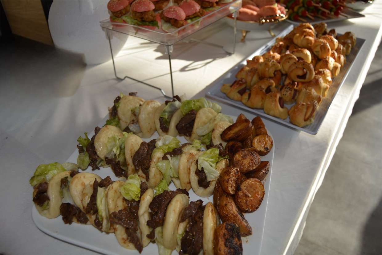 A platter of beef bao buns with lettuce, served alongside roasted potato wedges